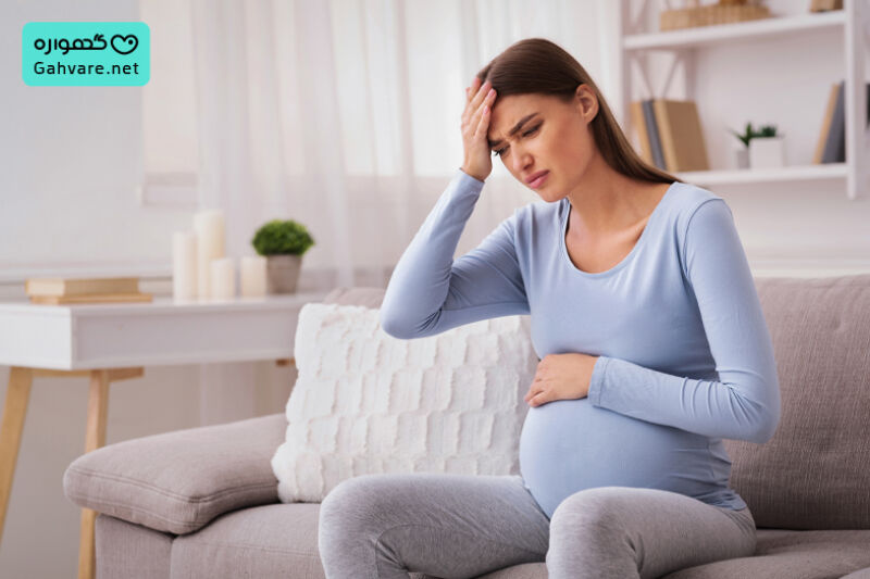 خانمی باردار نشسته روی میز با سر درد
